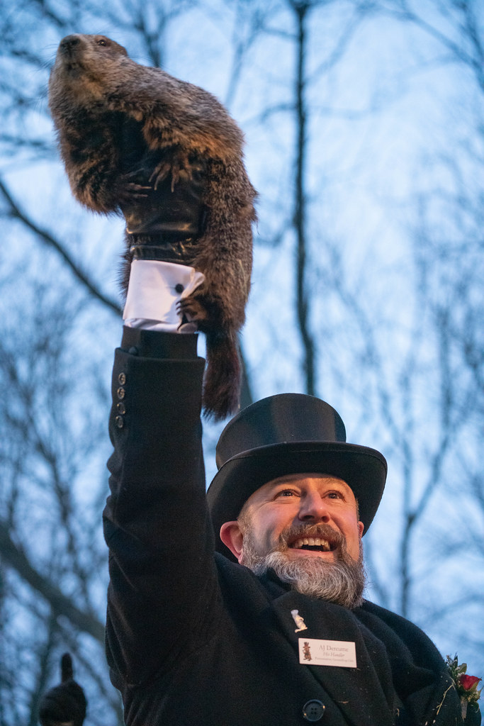 A man holding a groundhog above his head with one hand